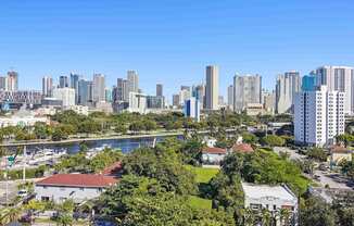 1- & 2-Bedroom Apartments for Rent in Miami, FL – Riverview One Apartments – A cityscape with a mix of residential and commercial buildings and view of the river in Miami, FL
