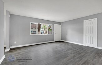 the living room of an apartment with grey walls and a white door