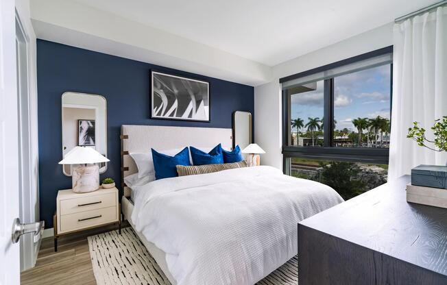 A calming primary bedroom with layered textures and palm-lined views, designed for everyday comfort at Modera Aventura.