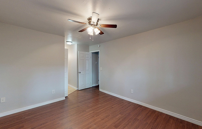 Inviting room with sleek hardwood floors, neutral walls, and modern ceiling fan creating a cozy atmosphere.