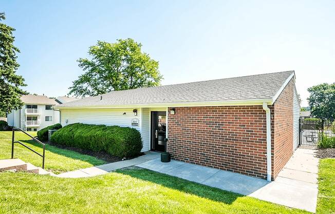 a small brick building with a driveway and grass