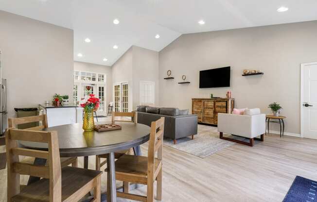 a living room and dining room with a table and chairs and a tv on the wall