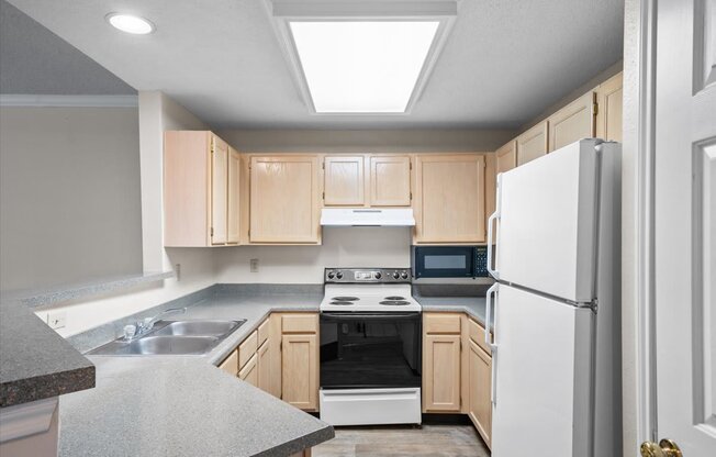 A kitchen with a white refrigerator, sink, and stove.