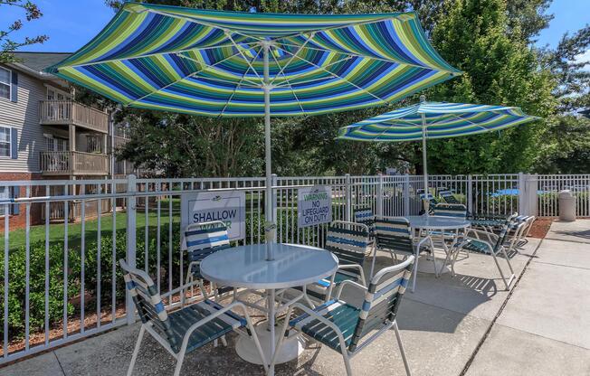 Outdoor table and chairs under an umbrella at Ashley Oaks Apartments in Greensboro, North Carolina