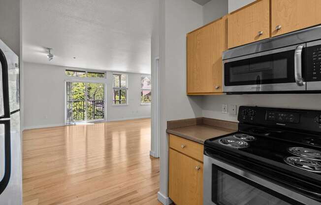 an empty kitchen and living room with wood flooring and appliances