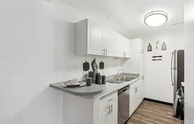 A kitchen with white cabinets and a wooden floor.