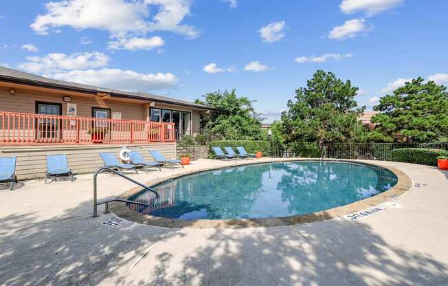 A small pool with a metal railing and a few chairs.