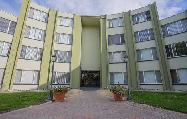 the entrance to an apartment building with a walkway and potted plants