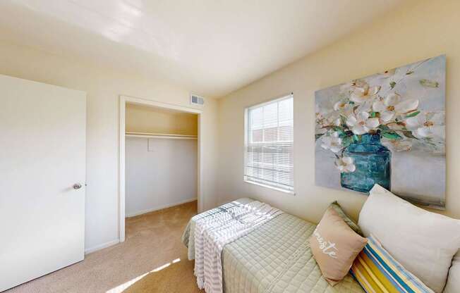 A bedroom with a bed, pillows, and a painting on the wall.