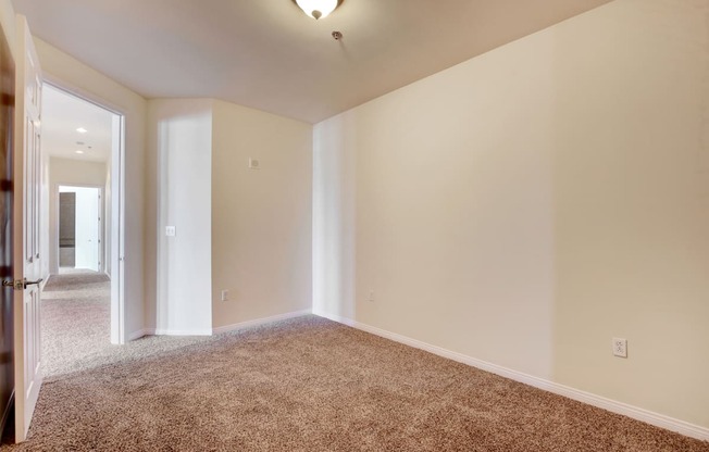 A large, empty room with carpeted flooring and white walls.