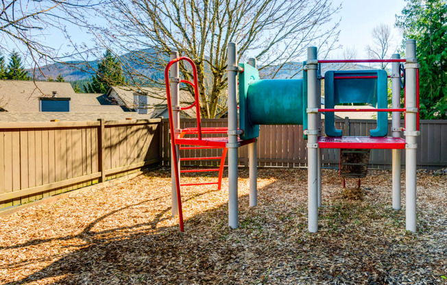 a playground with a slide and chairs in a backyard