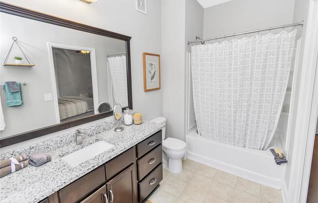 Full bathroom with hard floors, a large counter with wooden cabinetry, and bathtub shower combo