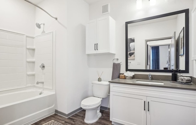 a bathroom with white cabinets and a toilet and a bath tub