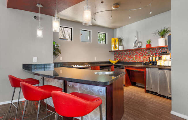A kitchen with a bar area and red chairs.