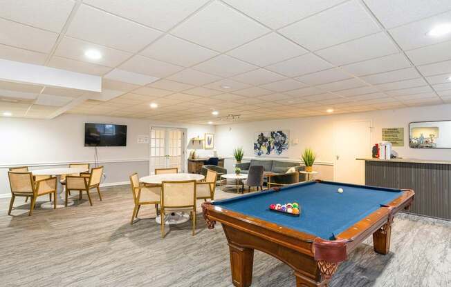 A pool table is in the middle of a room with a TV and a dining table.