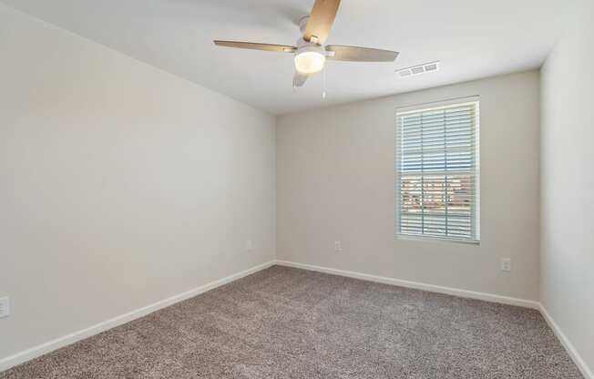 an empty room with a ceiling fan and a window