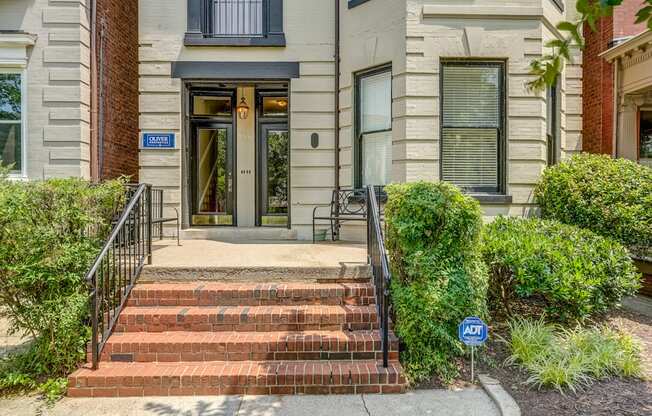 The front of a building with a brick facade and a black railing.