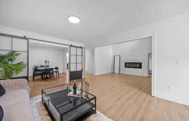 A modern living room with a glass coffee table and a fireplace.