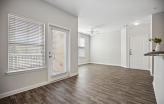 an empty living room and dining room with white walls and wood flooring