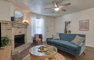 A living room with a blue couch and a fireplace.