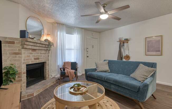 A living room with a blue couch and a fireplace.