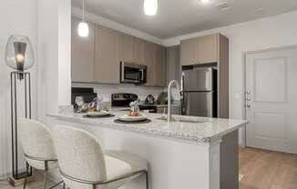 a kitchen with granite counter tops and a bar with two white chairs