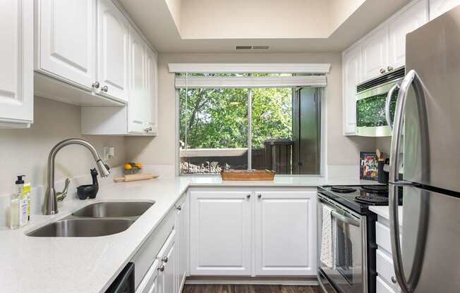 a kitchen with white cabinets and a sink and a window