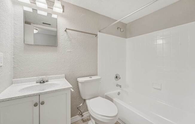 A white bathroom with a toilet, sink, and bathtub.