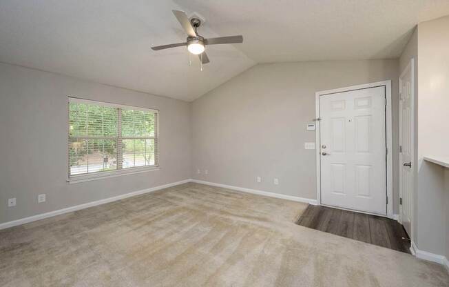 A room with a ceiling fan and a door leading to another room.