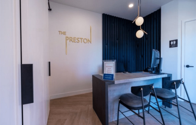 a desk and chairs in a room with the logo on the wall  at The Preston at Hillsdale, San Mateo, California