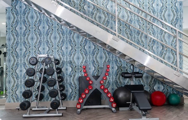 A gym with a blue patterned wallpaper and a variety of exercise equipment.