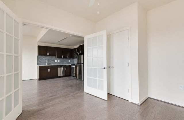 an empty living room with a kitchen in the background