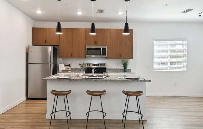 a kitchen with a island and three bar stools in front of a kitchen counter at Gibson Oaks, Lakeland, 33809