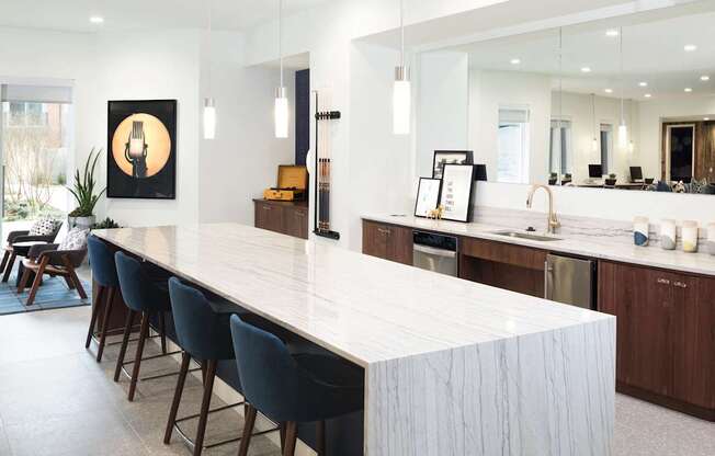 a large white kitchen with a long island and blue chairs