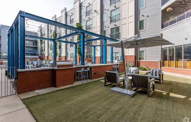 a patio with tables and chairs and a bar in front of an apartment building