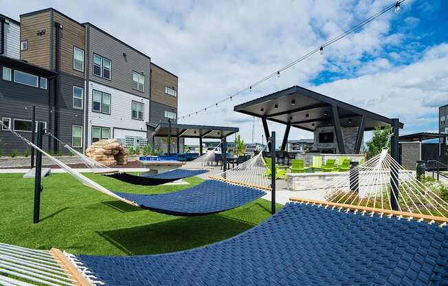 a playground with hammocks and lawn chairs and buildings in the background