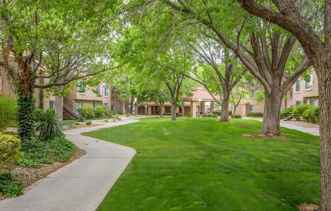 a yard with green grass and trees with apartments in the background