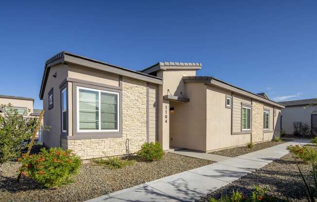 a beige house with a sidewalk in front of it at Grandstone at Sunrise, Peoria, AZ