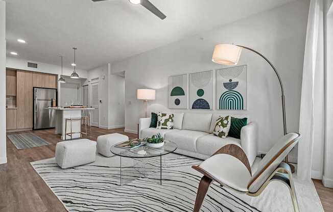 A modern living room with a white sofa, a glass coffee table, and a striped rug.