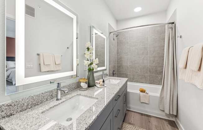 a white and gray bathroom with two sinks and a shower