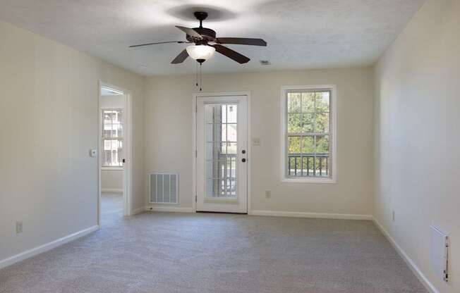 A room with a ceiling fan and two windows.