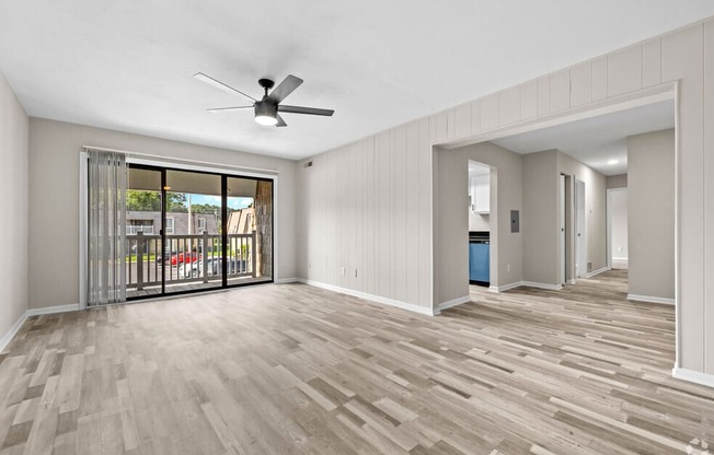 an empty living room with a sliding glass door to a balcony at Bayville Apartments, Virginia Beach