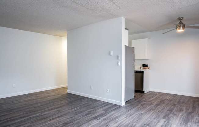 a living room and kitchen with white walls and wood floors