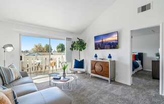 an open living room with a couch and a tv and a balcony