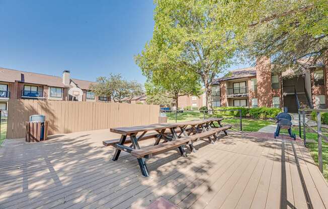 A wooden picnic table is in the middle of a wooden deck.