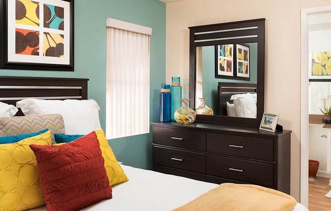 A bedroom with a bed, dresser, and mirror.