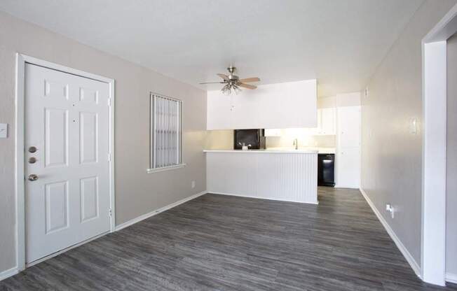 A room with a white door, a ceiling fan, and a window with blinds.
