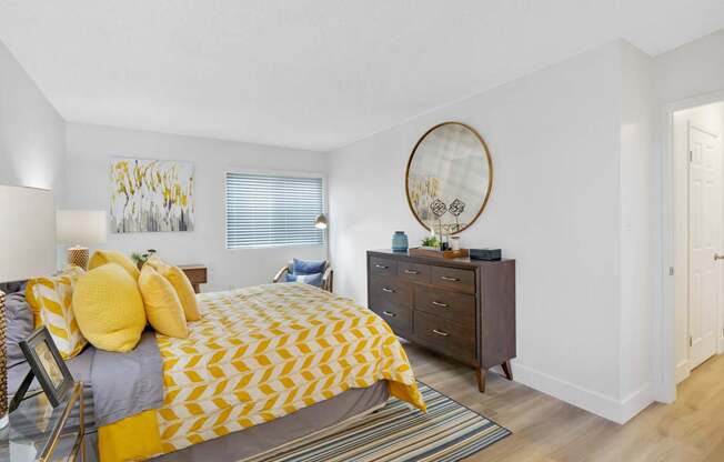 A bedroom with a bed, dresser, and mirror at Verandas Apartments, West Covina, CA, 91791