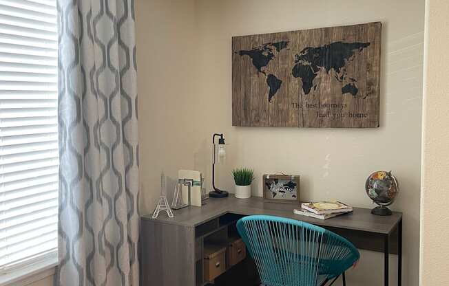 A room with a wooden world map on the wall and a blue chair.