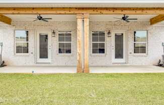 the front porch of a brick house with two ceiling fans and windows